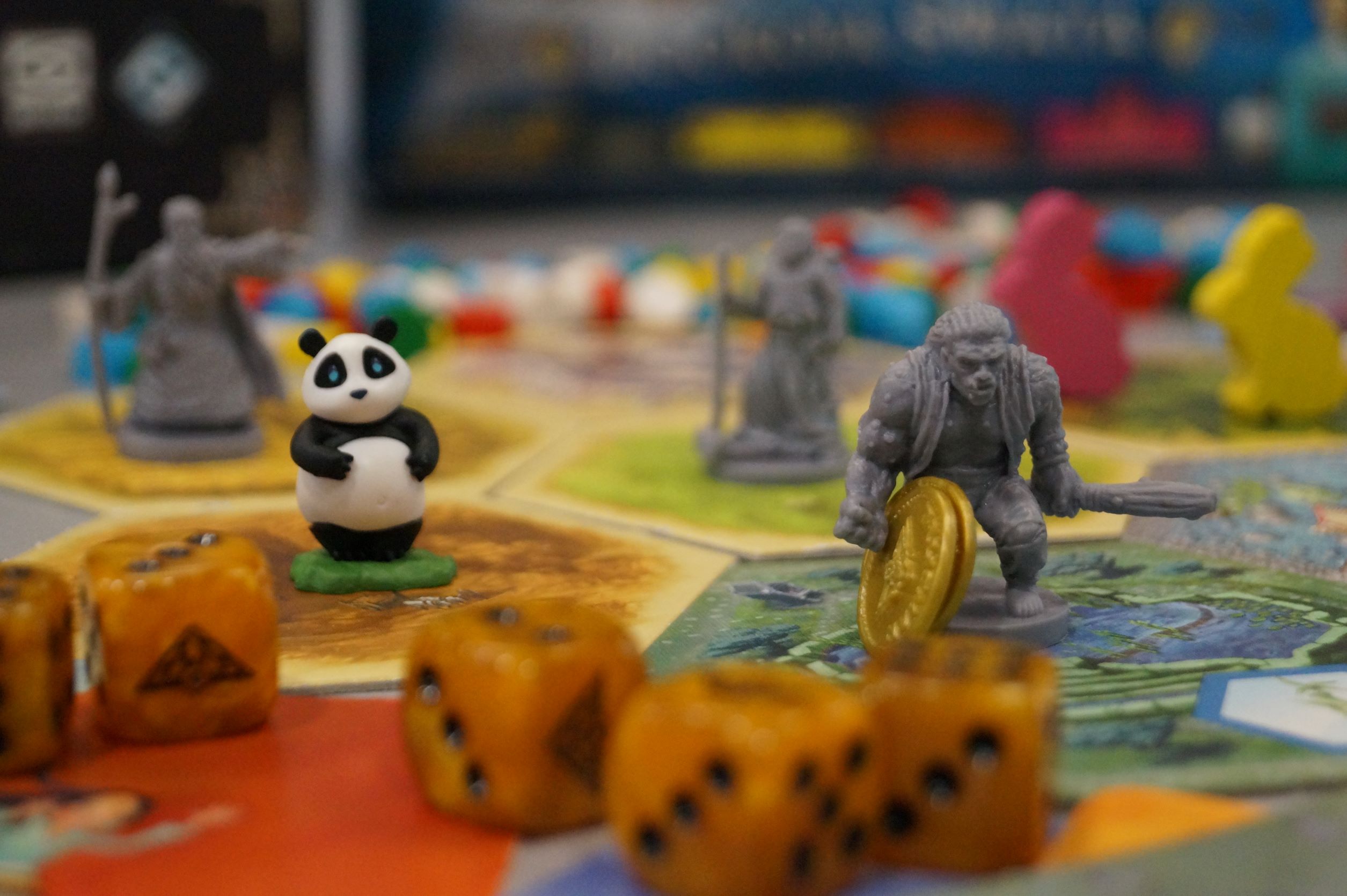 Plansza do gry. Na pierwszym planie stoją dwie figurki - miś panda i wojownik.